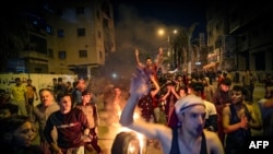 Palestinians parade a burning tire as they shout slogans during a rally in Gaza City, April 24, 2021, condemning overnight clashes in Israeli-annexed east Jerusalem.