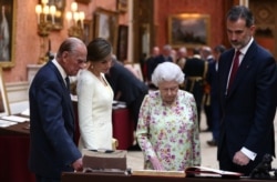 FILE - Britain's Queen Elizabeth II, Prince Philip, Duke of Edinburgh and Spain's King Felipe and Queen Letizia look at a display of Spanish items from the Royal Collection at Buckingham Palace, London, July 12, 2017.