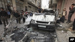 Palestinians inspect the damage to a vehicle after an Israeli air strike in Gaza City April 9, 2011