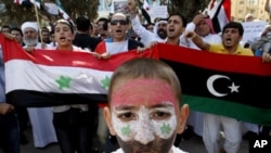 Syrians living in Jordan hold Syrian and the Kingdom of Libya flags shout slogans against Syria's President Bashar al-Assad during a protest outside the United Nations office in Amman October 15, 2011.