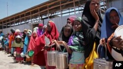 FILE - In this photo taken Feb. 25, 2017, displaced Somali girls who fled the drought in southern Somalia stand in a queue to receive food handouts at a feeding center in a camp in Mogadishu, Somalia.