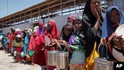 FILE - Displaced Somali girls who fled the drought in southern Somalia stand in a queue to receive food handouts at a feeding center in a camp in Mogadishu, Somalia, Feb. 25, 2017.