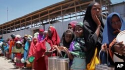 FILE - Displaced Somali girls who fled the drought in southern Somalia stand in a queue to receive food handouts at a feeding center in a camp in Mogadishu, Somalia, Feb. 25, 2017.