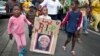 A young girl with a placard showing the face of Nelson Mandela and referring to his clan name "Madiba", marches with others to celebrate his life, in the street outside his old house in Soweto, Johannesburg, South Africa, Dec. 6, 2013. 