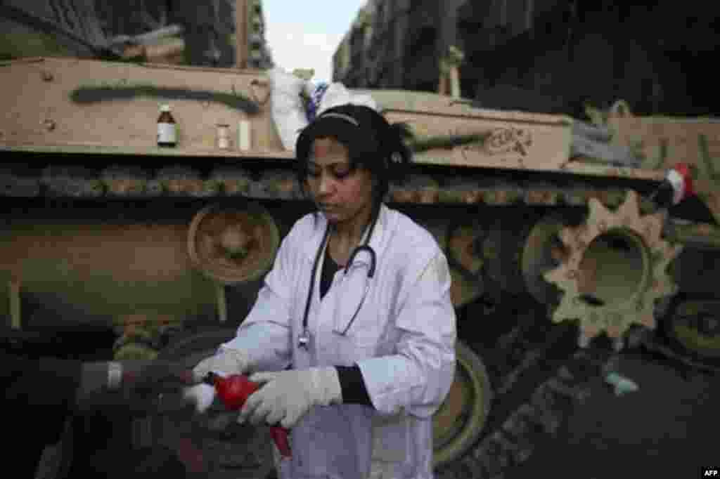 An Egyptian doctor gives out medical supplies in front of an army tank during clashes in Tahrir, or Liberation square, in Cairo, Egypt, Wednesday, Feb. 2, 2011. Several thousand supporters of President Hosni Mubarak, including some riding horses and camel