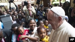 FILE- Pope Francis is cheered by children during his visit to Kangemi, one of the 11 slums dotting Nairobi, Kenya, Friday, Nov. 27, 2015.