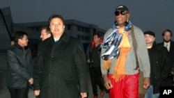 Mantan bintang NBA Dennis Rodman didampingi Wakil Menteri Olahraga Korea Utara, Son Kwang Ho, saat tiba di Pyongyang, Korea Utara (19/12). (AP/Kim Kwang Hyon)