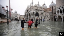 Personas vadean a través del agua en la inundada Plaza de San Marcos en Venecia, Italia, el miércoles 13 de noviembre de 2019. El nivel de marea alta alcanzó 187 centímetros (74 pulgadas) el martes 12 de noviembre de 2019, lo que significa que más del 85% de la ciudad se inundó.