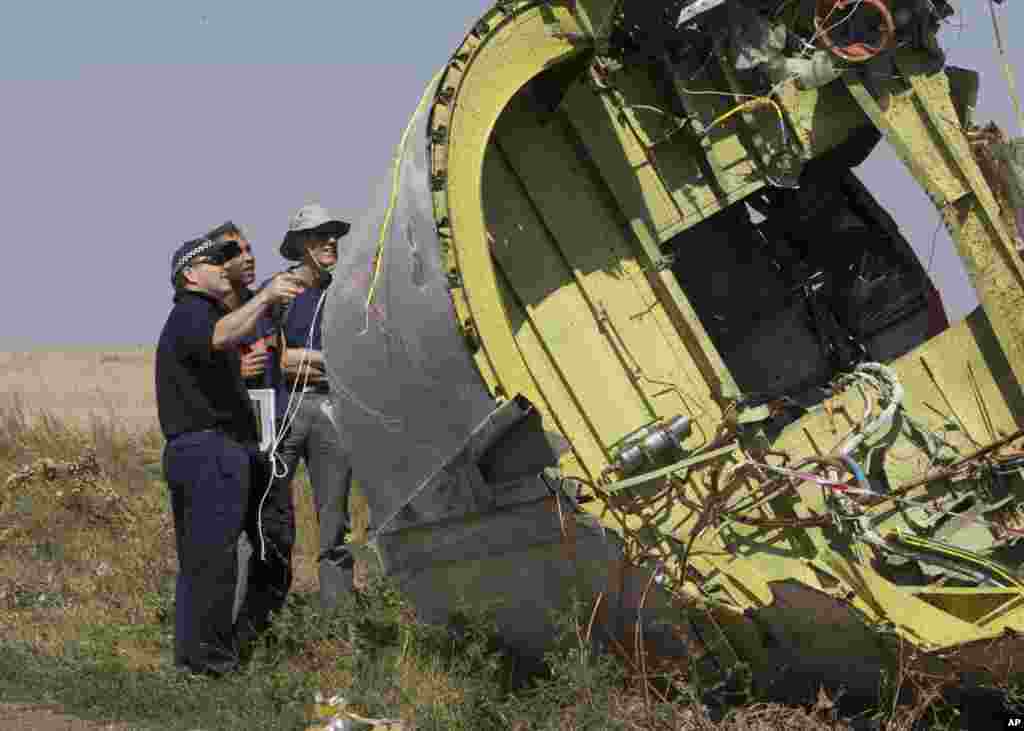 Australian and Dutch experts examine a piece of the Malaysia Airlines plane, near the village of Hrabove, Donetsk region, eastern Ukraine, Aug.1, 2014.&nbsp;