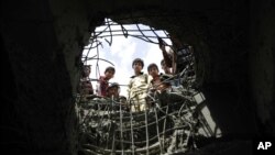 Wavulana wananchungulia kwenye shimo ambalo limetobolewa na shambulizi la anga lililofanywa na Saudi Arabi kwenye daraja huko Sanaa, Yemen. 