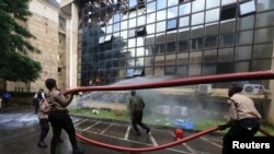 Road safety officers help to carry a hose at the scene of the fire which broke out at the headquarters of the Nigeria Football Federation in Abuja, August 20, 2014.