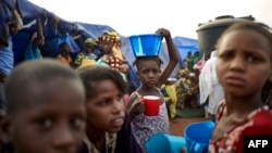 FILE - A girl balances a bowl of food on her head at an Internally Displaced People's (IDP) camp in Faladie, where hundreds have found refuge after fleeing inter-communal violence in central Mali, May 14, 2019.