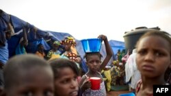 Une fille met en équilibre un bol de nourriture sur sa tête dans un camp de personnes déplacées à l'intérieur du camp de Faladie, où des centaines de personnes ont trouvé refuge après avoir fui la violence intercommunautaire dans le centre du Mali, le 14 mai 2019.