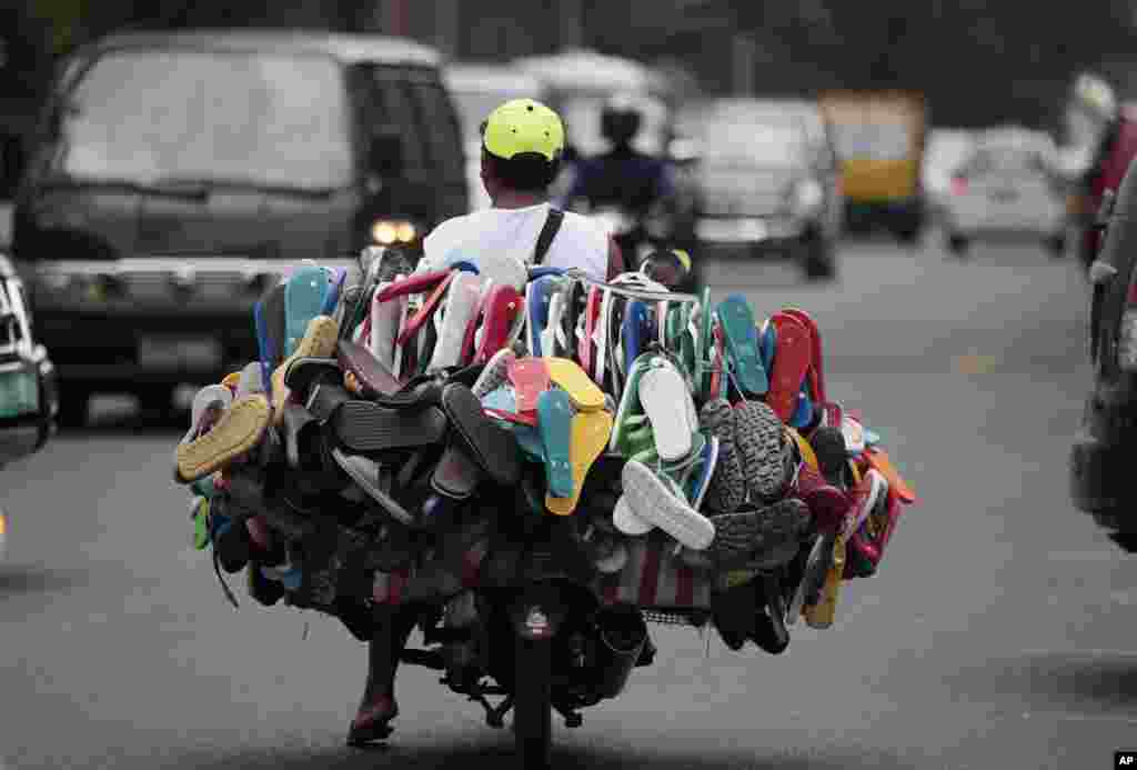 Prodavac raznoraznih sandala, japanki i papuča na jednoj od ulica Manile, Filipini. Svoju bogatu ponudu prevozi na motociklu koji jedva da se vidi.