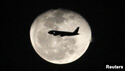 A passenger jet flies in front of the moon in Bogota, Colombia on Nov. 1, 2012. 