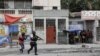 La gente se aglomera en una esquina mientras la policía patrulla las calles después de que pandilleros intentaran atacar una comisaría, en Puerto Príncipe, Haití, el 25 de abril de 2023.