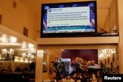 FILE - A tweet by U.S. President Donald Trump about the coronavirus is seen on a Chinese TV broadcast inside a restaurant in the Chinatown section of San Francisco, California, Feb. 24, 2020. Trump tweeted before markets fell due to virus fears.