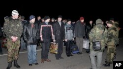 Russians, back to camera at right, and Ukrainians prepare for an exchange of prisoners outside Donetsk in eastern Ukraine, Friday Dec. 26, 2014.