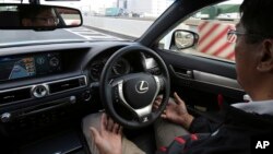 FILE - An employee of Toyota Motor Corp., drives automated driving test vehicle during a test drive of Toyota's self-driving technologies in Tokyo, Oct. 6, 2015. 