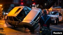 New York Fire Department officers watch as New York Police Department (NYPD) officers work to right a truck that had flipped on its side in an accident in New York, April 26, 2013.