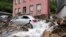 Mobil tertutup dengan puing-puing yang terbawa oleh banjir sungai 'Nahma' di Hagen, Jerman, Kamis, 15 Juli 2021. (AP Photo/Martin Meissner)
