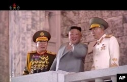 In this image made from video broadcast by North Korea's KRT, North Korean leader Kim Jong Un, center, watches a military parade marking the 75th anniversary of the country's ruling Workers' party, in Pyongyang, Oct. 10, 2020.