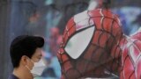 A man wearing a mask as a precaution against the Middle East Respiratory Syndrome (MERS) virus walks by a Spiderman poster in Seoul, South Korea.