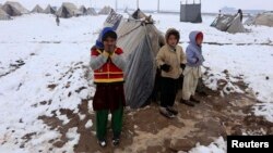 FILE - Internally displaced Afghan children stand outside their shelter in the cold at a refugee camp on the outskirts of Herat city.