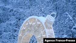 A woman walks past a light arch set up for the upcoming New Year and Christmas holidays in front of snow-covered trees after heavy snowfall in Moscow, Russia.