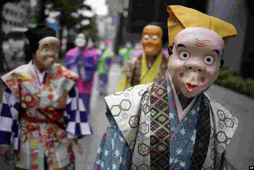 Para seniman yang mengenakan topeng badut tradisional bersiap untuk berbaris selama festival Shinto tahunan di kuil Kotohiragu di distrik bisnis Toranomon, Tokyo, Jepang. (AP)&nbsp;