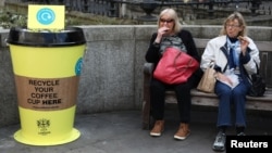 People sit next to a new coffee cup recycling point in London, April 3, 2017. British lawmakers are considering a "latte levy" to encourage reusable cups and recycling.