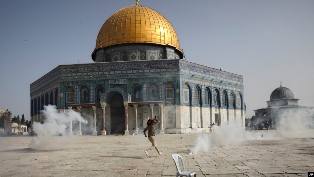 Seorang pria Palestina melarikan diri dari gas air mata saat bentrok dengan pasukan keamanan Israel di depan Masjid Shakhrah (Kubah Batu/Dome of the Rock) di kompleks Masjid Al Aqsa di Kota Tua Yerusalem, Senin, 10 Mei 2021. (AP Photo/Mahmoud Illean)