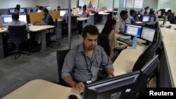 FILE - Employees of ISGN work at their stations inside the company headquarters in the southern Indian city of Bangalore.