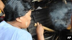 Fuel-efficient stoves use significantly less firewood than a traditional three-stone stove. This woman in Myanmar is using a pipe to help increase the fire's flames to cook the food.