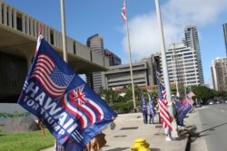 Supporters of President Donald Trump carry US and Trump campaign flags during a protest outside the Hawaii State Capitol in Honolulu on Jan. 6, 2021.