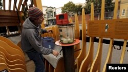 Scientist Eric Dimond of the San Francisco Eploratorium, cranks a desalination pump by hand to display the process of turning salt water to fresh water at a public parklet - a space the size of two parking spots in the Mission neighborhood.