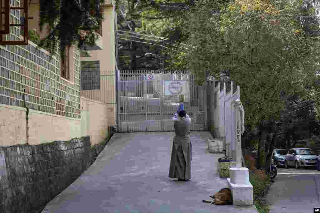 An exile Tibetan woman prays in front of a closed gate of the Tsuglakhang temple in Dharmsala, India, Tuesday, Oct. 13, 2020. The temple, which is situated in the same compound as the residence of Tibetan leader the Dalai Lama is closed to visitors due to