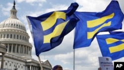 FILE - In this July 26, 2017, photo, people with the Human Rights Campaign hold up "equality flags" during an event on Capitol Hill in Washington, in support of transgender members of the military.