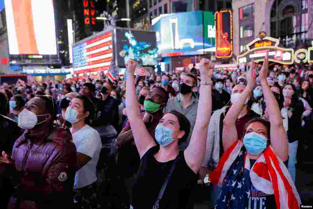 People react as they watch a speech by Democratic 2020 U.S. presidential nominee Joe Biden after news media announced that he has won the 2020 U.S. presidential election, on Times Square in New York.