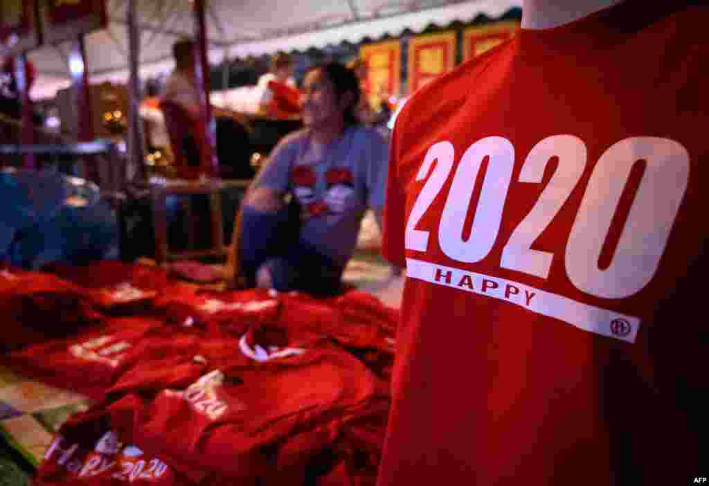 بینکاک کی ایک شاہراہ پر نئے سال 2020 کے موقع پر ایک دکاندار ٹی شرٹس فروخت کر رہا ہے &nbsp;