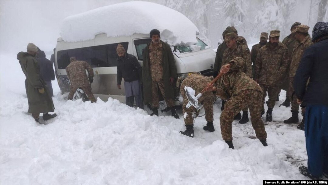 Seorang tentara membersihkan salju di bawah kendaraan yang terdampar setelah hujan salju lebat di Murree, Pakistan 8 Januari 2022. (Foto: Inter Services Public Relations/ISPR via REUTERS)