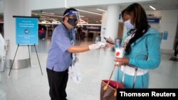 지난 4일 미국 로스앤젤레스 국제 공항(LAX)에서 여행안전요원이 코로나바이러스 감염 방지를 위해 탑승객에게 마스크를 나눠주고 있다.