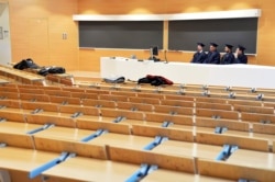 Examiners sit in an empty classroom as they listen to students defending their thesis on line, at the Politecnico University in Milan, Italy, March 5, 2020.