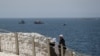 Sejumlah warga tampak berjalan di tepi pantai di wilayah Rosh Hanikra, dekat perbatasan Lebanon, ketika kapal angkatan laut Israel terlihat berlayar di laut Mediterania, pada 4 Mei 2021. (Foto: Reuters/Ammar Awad)