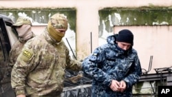 A Ukrainian sailor, right, is escorted by a Russian intelligence officer to a court room in Simferopol, Crimea, Nov. 27, 2018. 