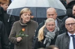 German Chancellor Angela Merkel arrives with a rose at a ceremony marking the 30th anniversary of the fall of the Berlin Wall, in Berlin, Germany, Nov. 9, 2019.