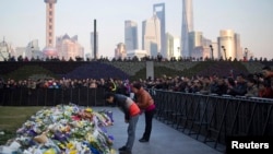 People bow during a memorial ceremony for people who were killed in a stampede incident during a New Year's celebration on the Bund, in Shanghai, Jan. 2, 2015.