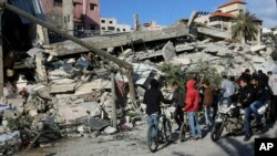 26일 팔레스타인자치지구인 가자지구에서 이스라엘의 보복 공습이 있은 후 주민들이 처참히 부서진 건물 주위에 모여있다. 