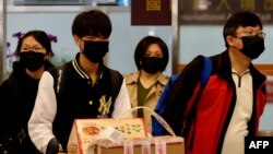 FILE - Passengers wearing masks to protect against the coronavirus arrive at Sungshan Airport, in Taipei, Taiwan, Jan. 22, 2020. Many Taiwanese who had lived abroad have returned home, feeling safer there from the pandemic's reach.