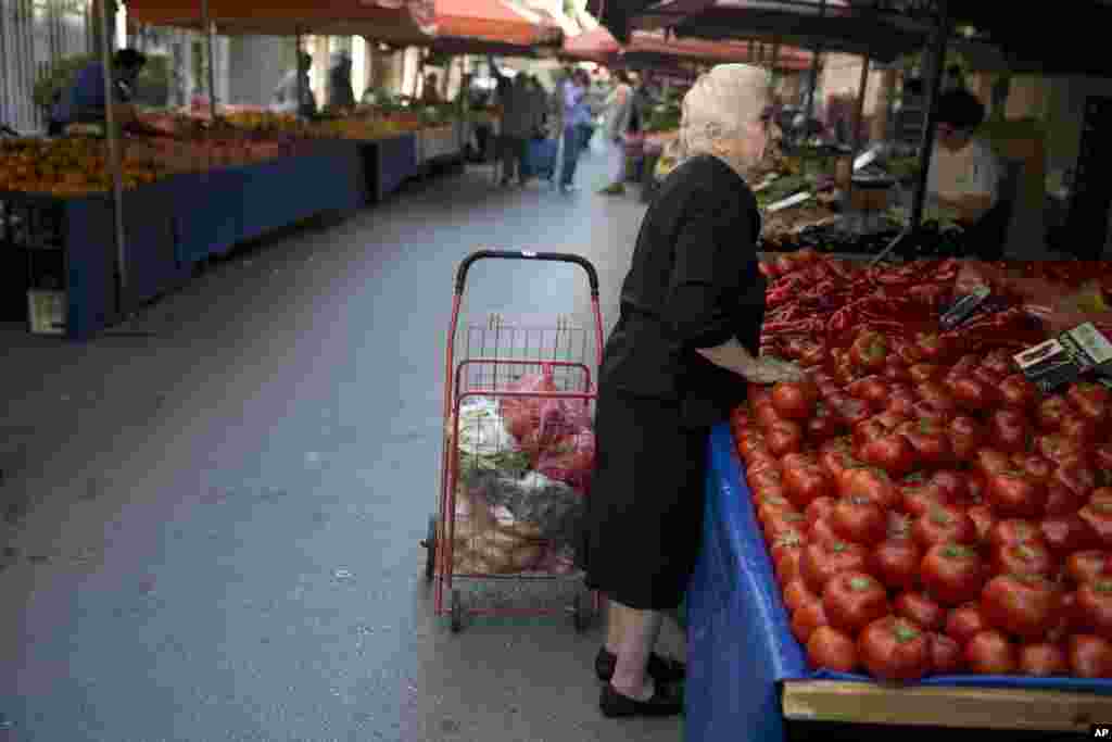 An elderly woman buys goods at an empty vegetable market in Athens, July 3, 2015.